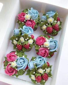 cupcakes decorated with flowers and strawberries in a box