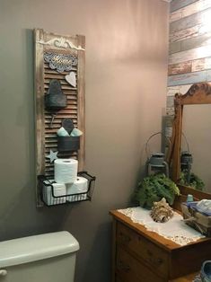 a bathroom with a toilet, mirror and wooden shutters on the wall above it