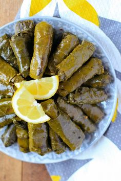 a plate full of stuffed grape leaves and lemon wedges