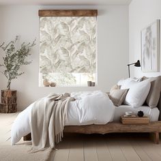 a bed with white sheets and pillows next to a window covered in leaves on the blinds