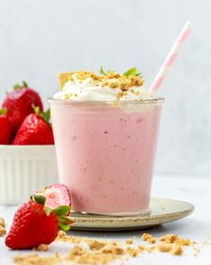 a strawberry milkshake with whipped cream and fresh strawberries on the side for garnish