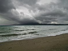 an ocean view with dark clouds over the water