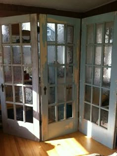 an open door in the corner of a room with wood flooring and glass doors