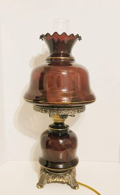 an antique lamp with a glass shade on it's base and gold trimmings