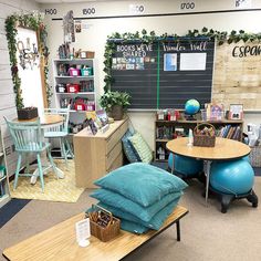 a room with tables, chairs and bookshelves on the walls is decorated with greenery