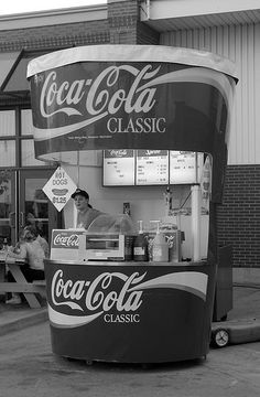 an old photo of a coca - cola stand in front of a building