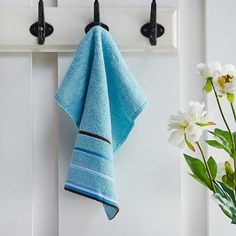 a towel hanging on a hook next to a vase with flowers