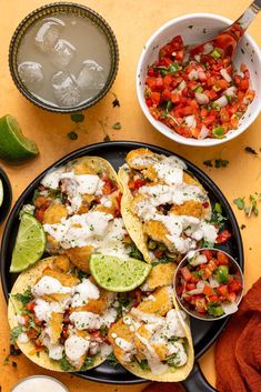 three tacos with guacamole, salsa and sour cream on the side