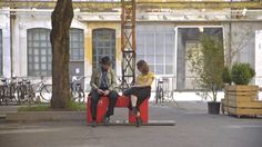 two people sitting on top of red benches