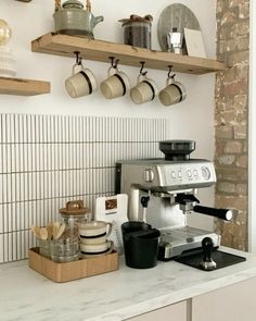 a coffee maker sitting on top of a counter next to pots and pans hanging from the wall