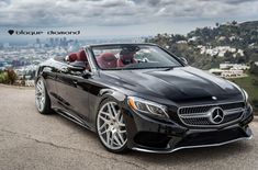 a black mercedes convertible parked on top of a hill