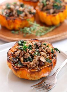 a white plate topped with stuffed squash covered in mushrooms and herbs next to a fork