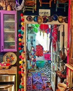 a kitchen with lots of colorful decorations on the walls and floor, along with an open door that leads to another room