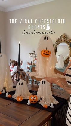 a woman standing in front of a table with halloween decorations on it and ghost candles