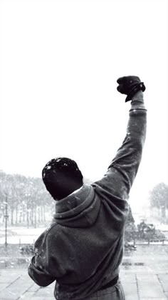 black and white photograph of a man raising his arms in the air with snow falling on him