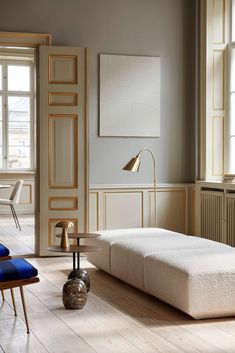 a living room filled with furniture and a lamp on top of a hard wood floor