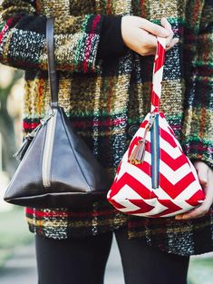 a woman holding two purses in her hands