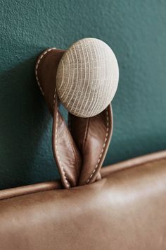 a brown leather purse with a white hat on the top and green wall behind it