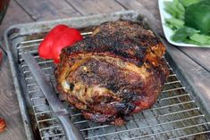 a large piece of meat sitting on top of a metal rack next to some vegetables