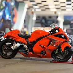 an orange motorcycle parked on top of a race track