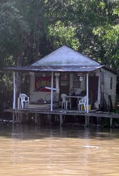 a house sitting on top of a wooden dock next to the water in front of trees