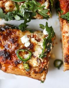 several slices of pizza on a white plate with green peppers and feta cheese toppings