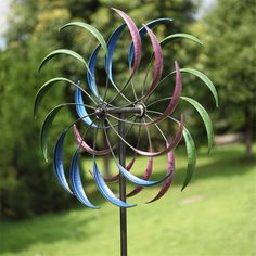 a colorful wind spinner sitting on top of a lush green field