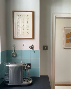 a blue tiled kitchen with a toaster and coffee maker on the counter in front of it