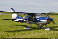 a small blue and white plane sitting on top of a lush green field