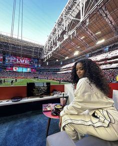 a woman sitting on a bench at a baseball game in an empty stadium with people watching from the bleachers