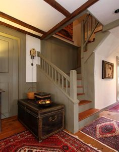 an old trunk sitting on top of a rug next to a stair case in a house