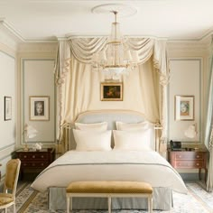 a white bed sitting under a chandelier in a bedroom