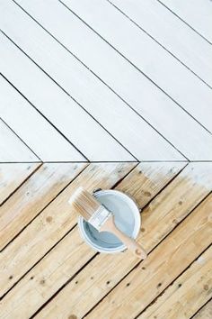 a paint can and brush sitting on top of a wooden floor