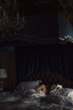 a woman laying in bed with her head on the pillow and arms behind her back