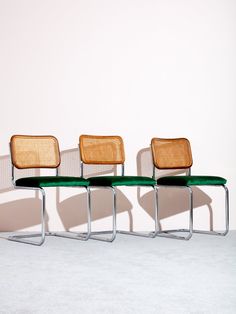 three chairs sitting next to each other in front of a white wall