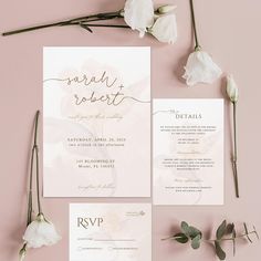 the wedding stationery is laid out with flowers and greenery