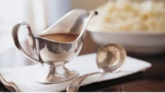 a silver gravy dish with spoons on a table