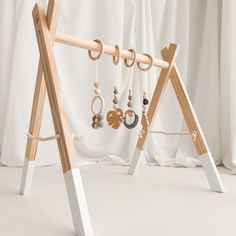 a wooden jewelry rack with earrings hanging from it's sides, in front of a white curtain