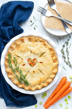 a pie on a plate with carrots next to it and a fork in the bowl