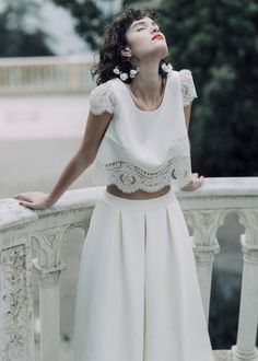 a woman standing on top of a balcony next to a white fence