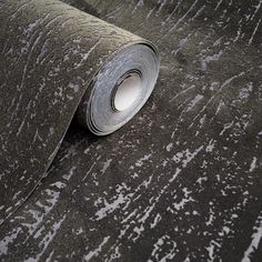 a roll of metallic foil sitting on top of a black wallpaper covered in white paint