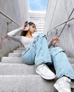 a woman wearing headphones sitting on some stairs