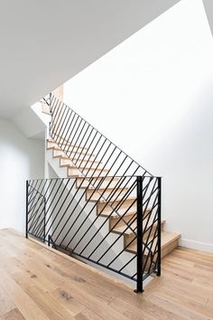 a stair case in the middle of a wooden floor next to a white wall and stairs