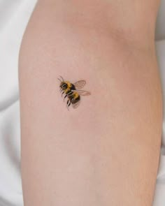 a close up of a person's arm with a bee tattoo on the side