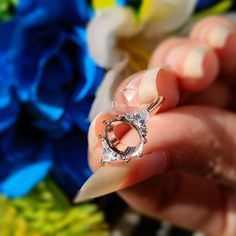 a woman's hand holding a diamond ring in front of blue and yellow flowers