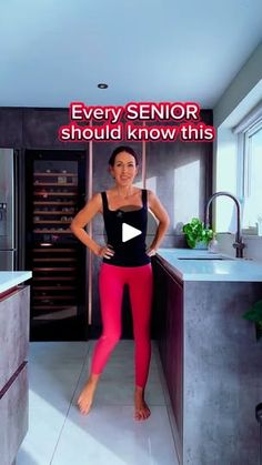 a woman is standing in the kitchen with her hands on her hips and smiling at the camera