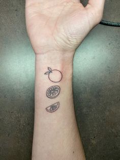 a person's hand with a small tattoo on the wrist and two slices of fruit