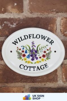 a sign on the side of a brick wall that says wildflower cottage with flowers