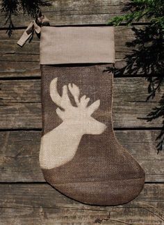 a christmas stocking with a moose on it hanging from a wooden wall next to evergreen branches