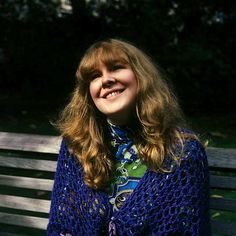 a woman sitting on top of a wooden bench